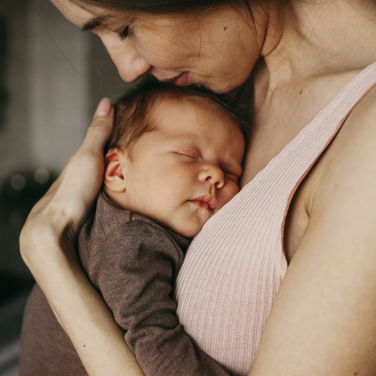 Bebis med brun ullbody i sin mammas famn